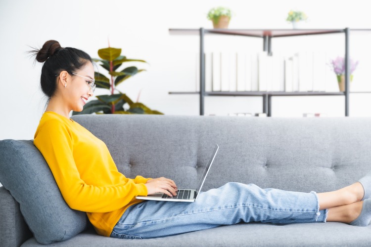 Young Asian woman using laptop on sofa